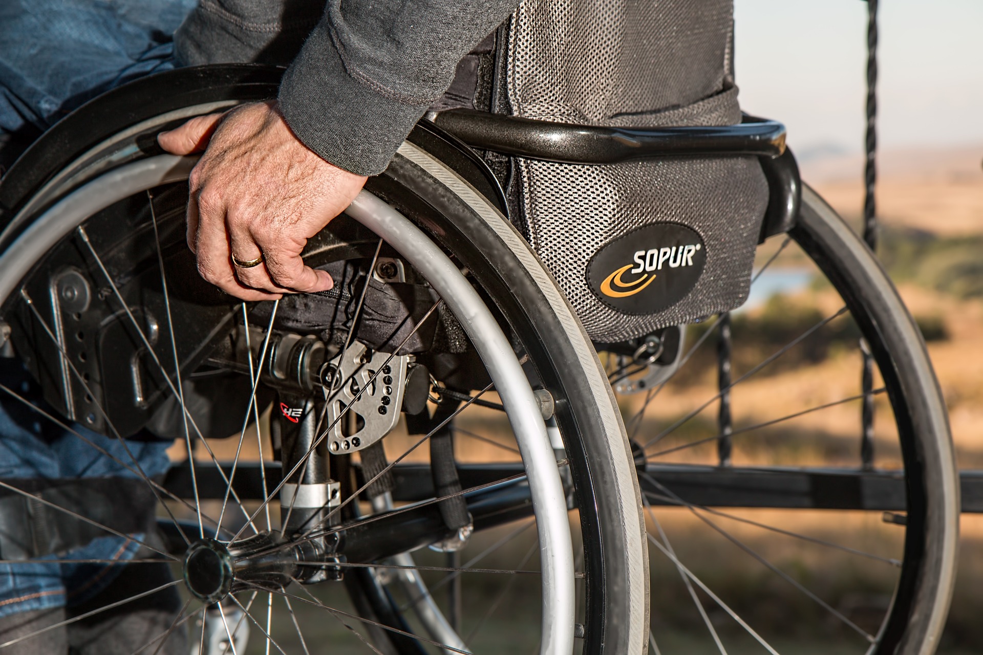a person sitting in a wheelchair, his hand resting on the wheelchair grip